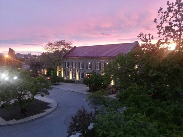 Exterior photo at dusk of the two-storey stone mill with a darkening red sky.